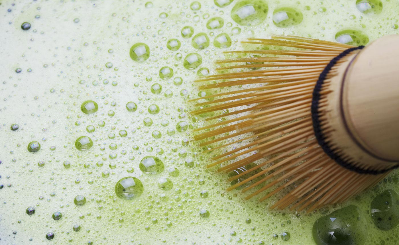 a whisked bowl of matcha green tea with a chasen whisk