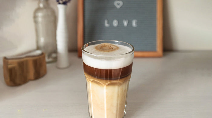 Hojicha latte on a table in front of a sign reading, 