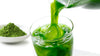 matcha green tea being poured into a glass. A bowl of matcha sits in the background.