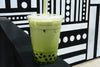 Matcha boba on a black and white patterned surface.
