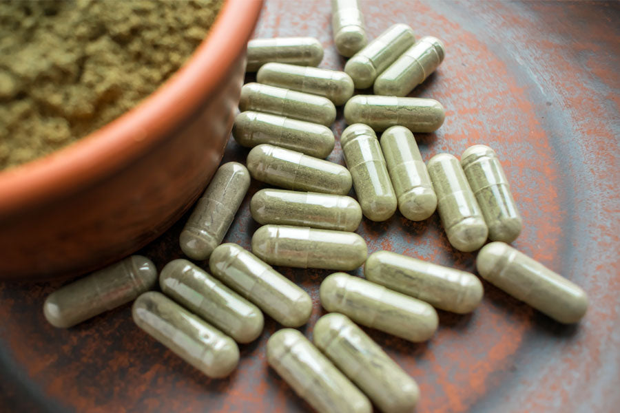 matcha in pill form next to a bowl of bulk matcha green tea