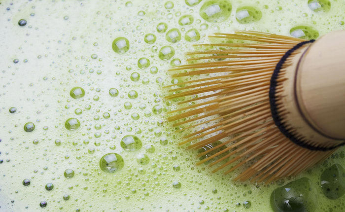 a whisked bowl of matcha green tea with a chasen whisk